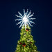 Decorated Christmas tree with a large snowflake light on a dark blue sky background