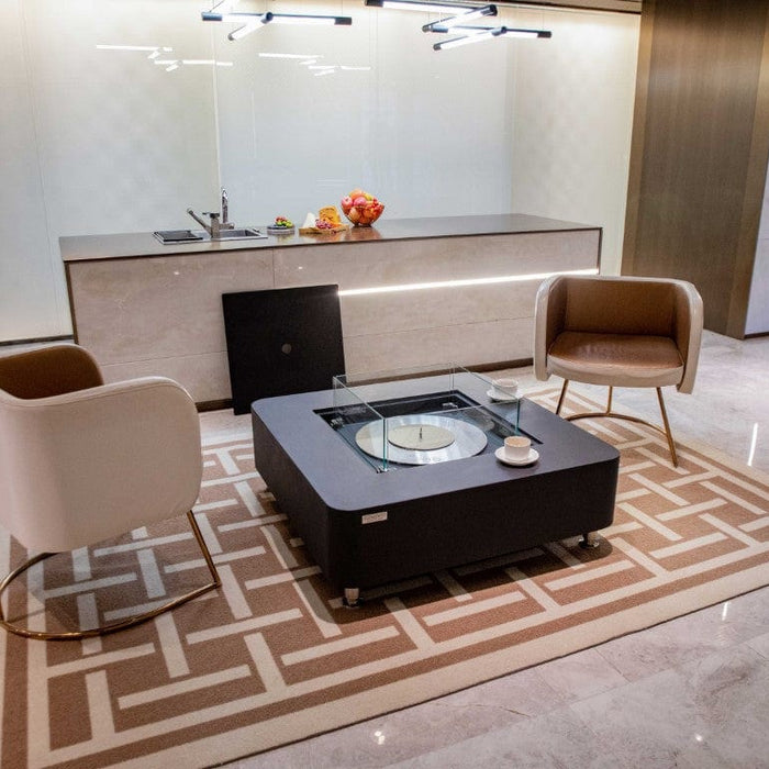Modern living room with a coffee table, chairs, and a kitchen in the background.