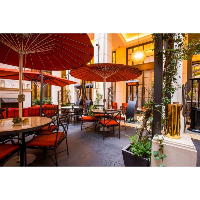 Outdoor seating area with red umbrellas and tables in an urban setting with Tungsten Portable Heaters in the background