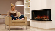 Woman reading in an armchair beside a Modern Flames 44 inch Landscape Pro Multi fireplace installed in a corner