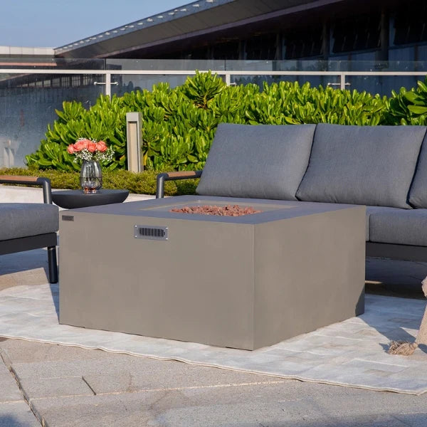 Outdoor patio setting with a fire pit table and gray cushions on a sofa.