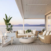 Outdoor patio with wicker furniture, cushions, and a scenic view of mountains and water. White Bromic Marine Heaters pictured flush mounted into the ceiling above