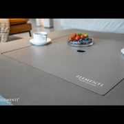 Gray countertop with a cup, saucer, and small dish of fruit on a blurred background